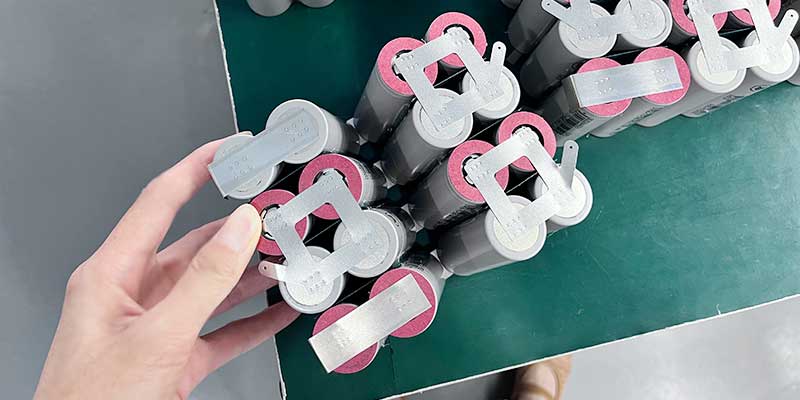 26700 LiFePO4 cells in 8S2P configuration with nickel strip welding and pink insulation rings during OEM battery pack assembly at Himax Electronics factory, for electric walker power systems